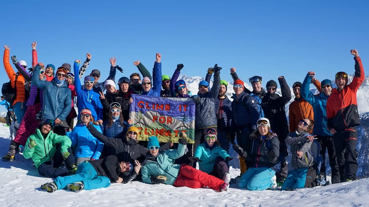 A group of Climb it for Climate participants surrounding a hand stitched banner, with their hands in the air.