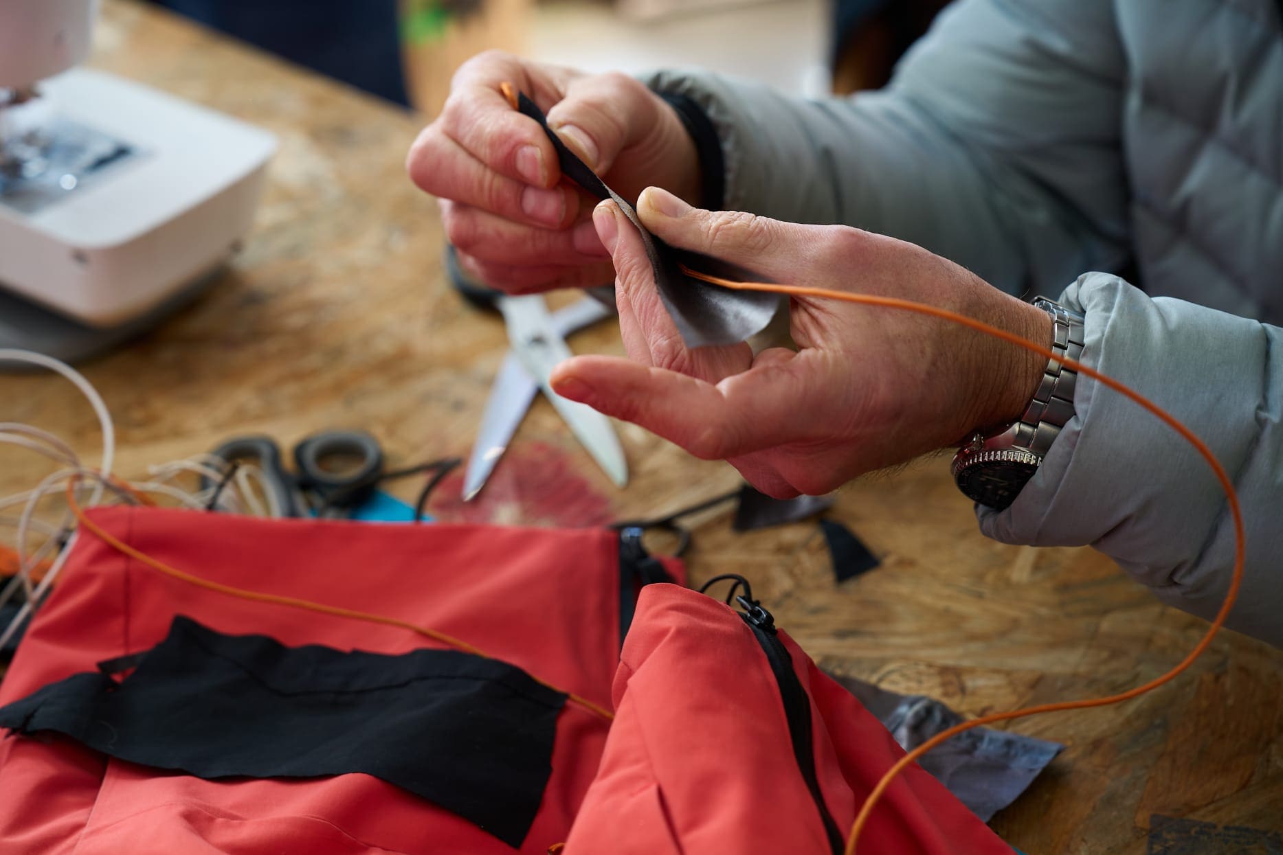 Two hands working on an adaptive ski jacket as part of the UN/PARA/LD project