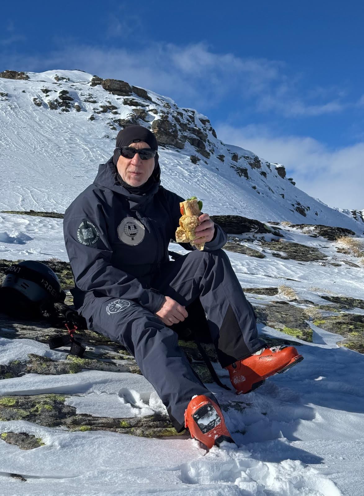 A skier eating a sandwich to refuel after a long hike