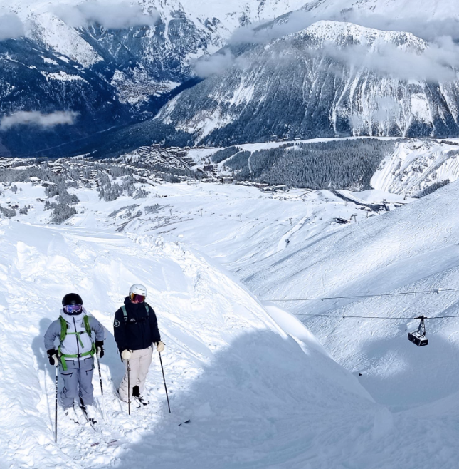 Skiers waiting to drop in to a powder filled couloir.